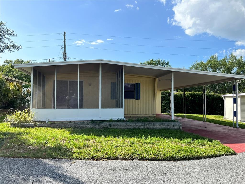 A single-story mobile home features a screened-in front porch and an attached carport — 36 MAGNOLIA COURT UNIT 4, SAFETY HARBOR, FL