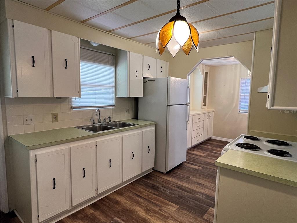A kitchen with white cabinets, green countertops, a white refrigerator, and a floral pendant light — 36 MAGNOLIA COURT UNIT 4, SAFETY HARBOR, FL