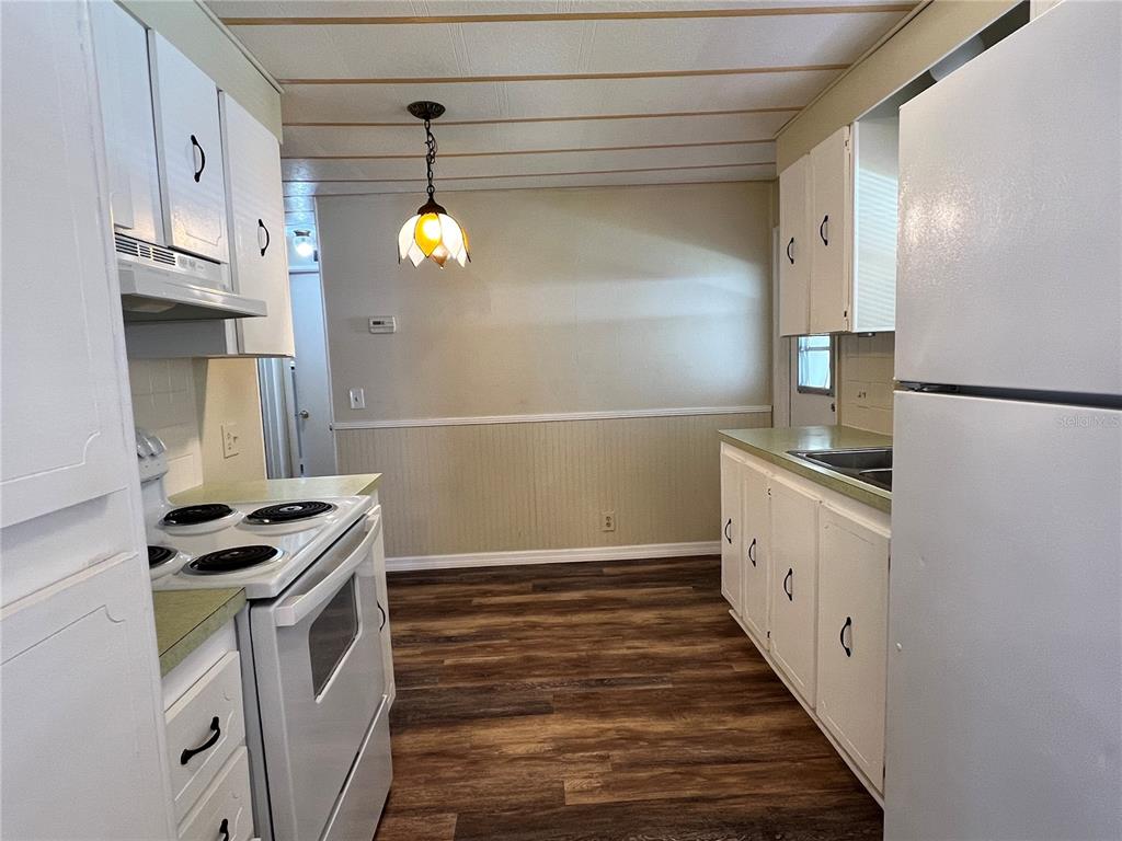 A kitchen features white cabinets, a white stove, a refrigerator, and wood-look flooring — 36 MAGNOLIA COURT UNIT 4, SAFETY HARBOR, FL