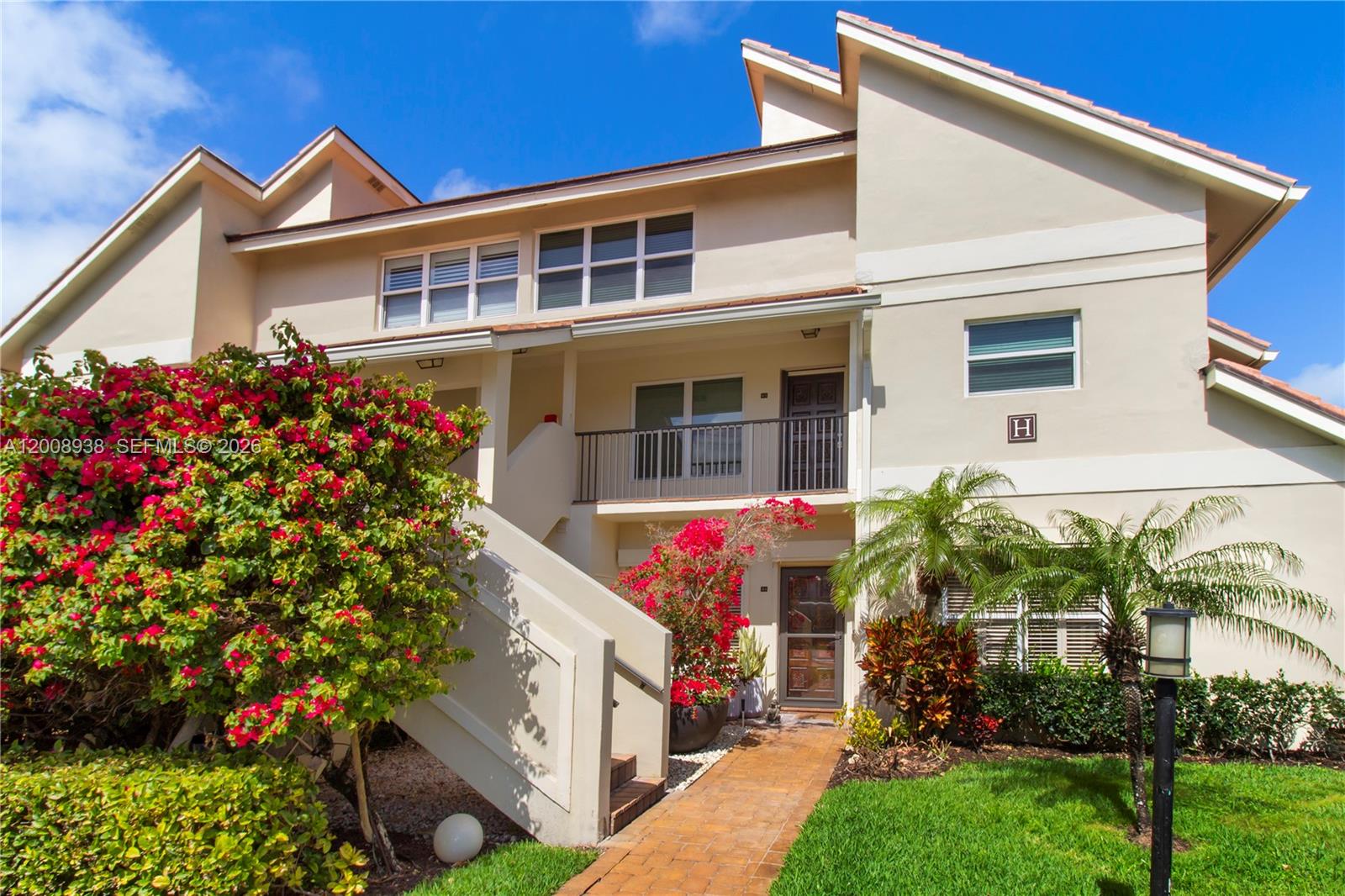 The exterior of a two-story residential building features a staircase, balcony, and landscaping — 4161 S Us Highway 1 # H1, Jupiter FL 33477, JUPITER, FL
