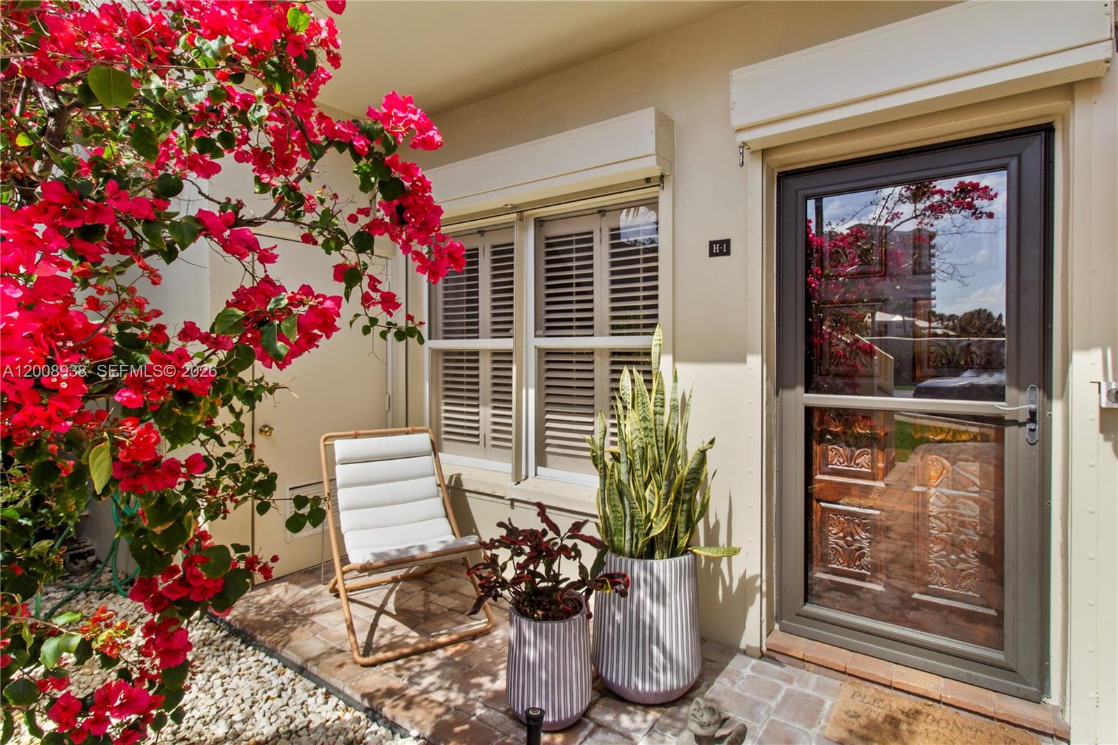 A patio features a white chair, potted plants, and a door with a storm door — 4161 S Us Highway 1 # H1, Jupiter FL 33477, JUPITER, FL