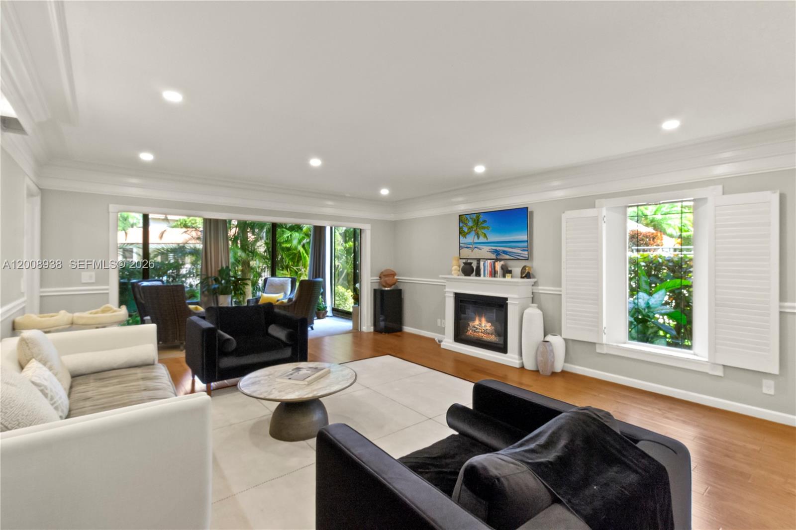 A living room features a fireplace, black armchairs, a white sofa, and large sliding doors — 4161 S Us Highway 1 # H1, Jupiter FL 33477, JUPITER, FL