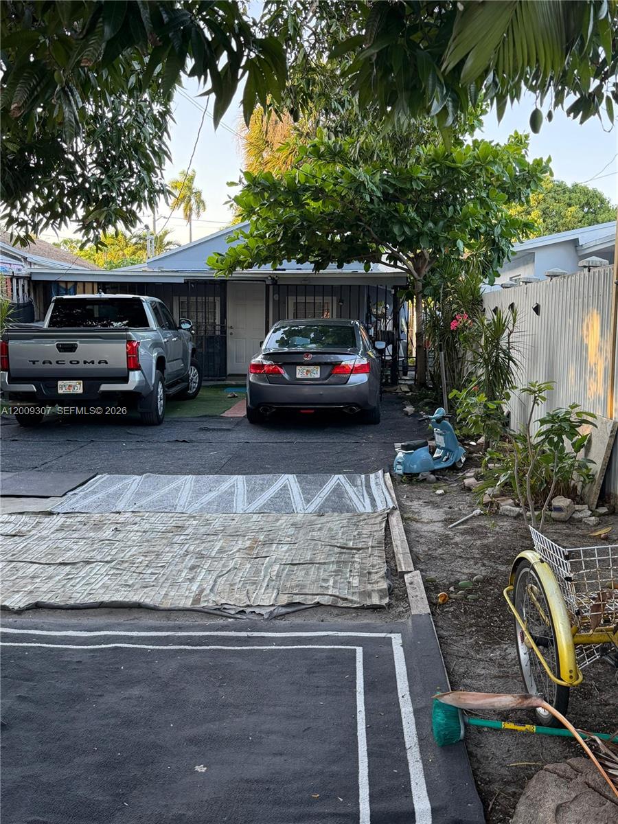 A driveway with two parked cars leads to the entrance of a single-story house — 1111 NW 26th St, Miami FL 33127, MIAMI, FL