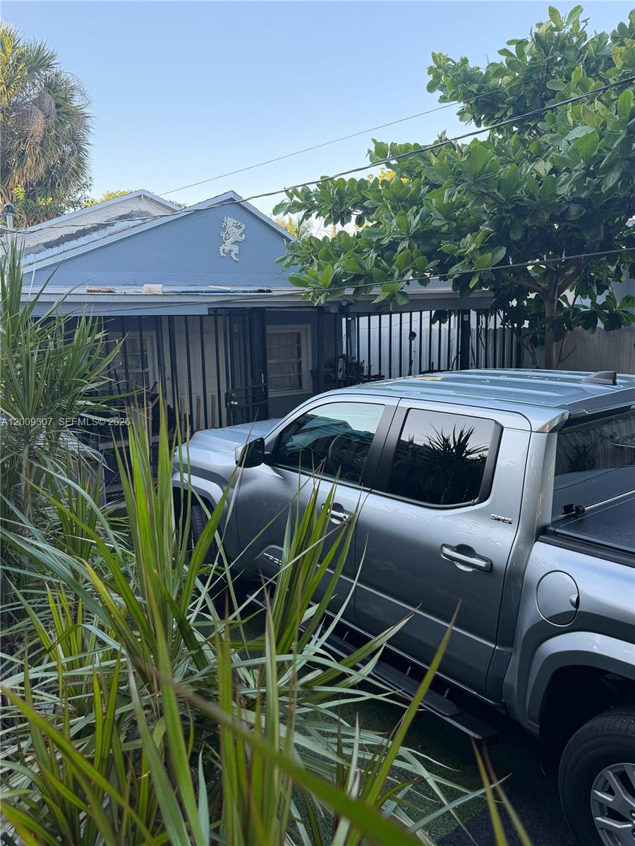A silver pickup truck is parked in front of a blue house with a metal gate — 1111 NW 26th St, Miami FL 33127, MIAMI, FL