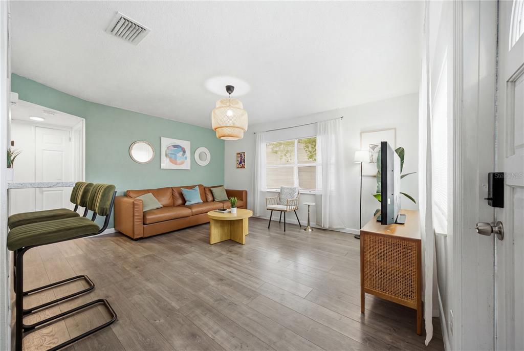 A living room features a green accent wall, a brown leather sofa, and wood flooring — 664 GRAY STREET S, ST PETERSBURG, FL