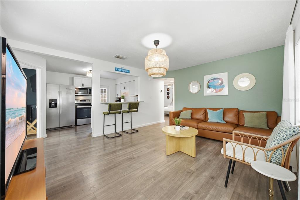 A living room with a brown leather sofa, green accent wall, and kitchen breakfast bar — 664 GRAY STREET S, ST PETERSBURG, FL