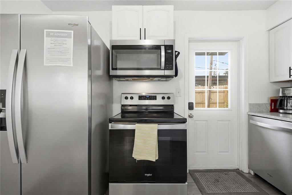 A kitchen features stainless steel appliances, white cabinets, and a door leading outside — 664 GRAY STREET S, ST PETERSBURG, FL