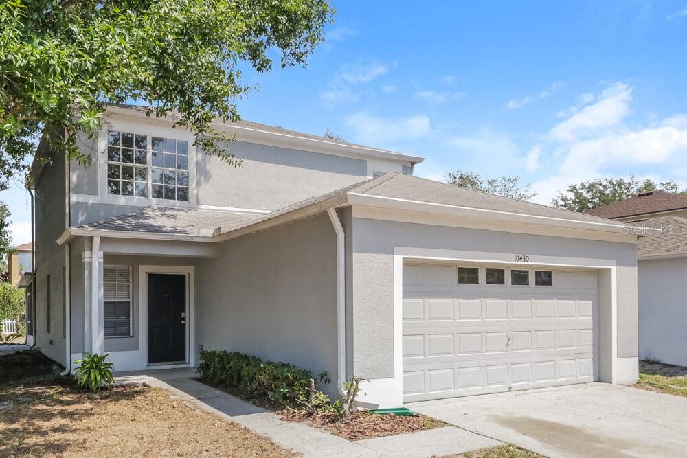 A two-story house with a gray stucco exterior, a single-car garage, and a front entrance — 10430 BLACKMORE DRIVE, TAMPA, FL