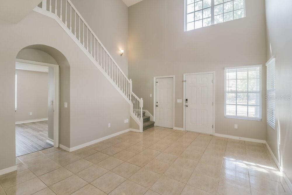 A bright entryway features tile flooring, a high ceiling, and a staircase with white railings — 10430 BLACKMORE DRIVE, TAMPA, FL