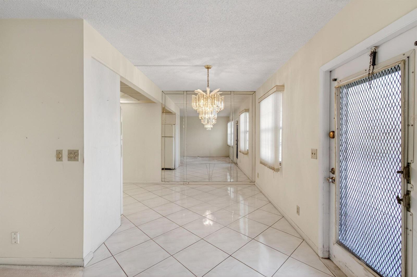 An entryway with white tile floors, a crystal chandelier, and mirrored wall panels — 3044 Lincoln, Boca Raton FL 33434, BOCA RATON, FL