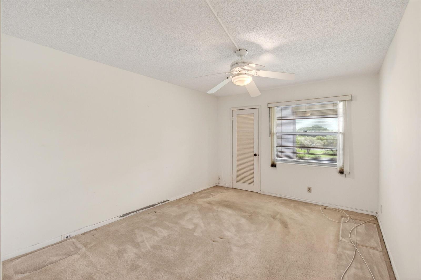 An empty bedroom features beige carpeting, white walls, a ceiling fan, and a louvered door — 3044 Lincoln, Boca Raton FL 33434, BOCA RATON, FL