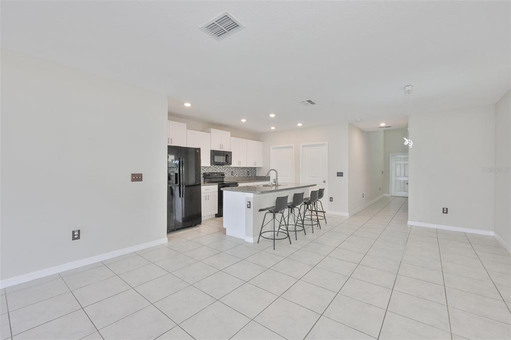 A kitchen with white cabinets, granite countertops, and a breakfast bar with four stools — 797 OLIVE CONCH STREET, RUSKIN, FL