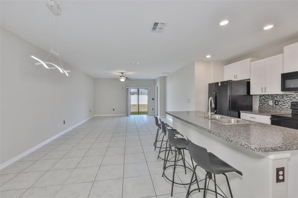 An open-concept kitchen and living area features tile flooring, granite countertops, and bar seating — 797 OLIVE CONCH STREET, RUSKIN, FL