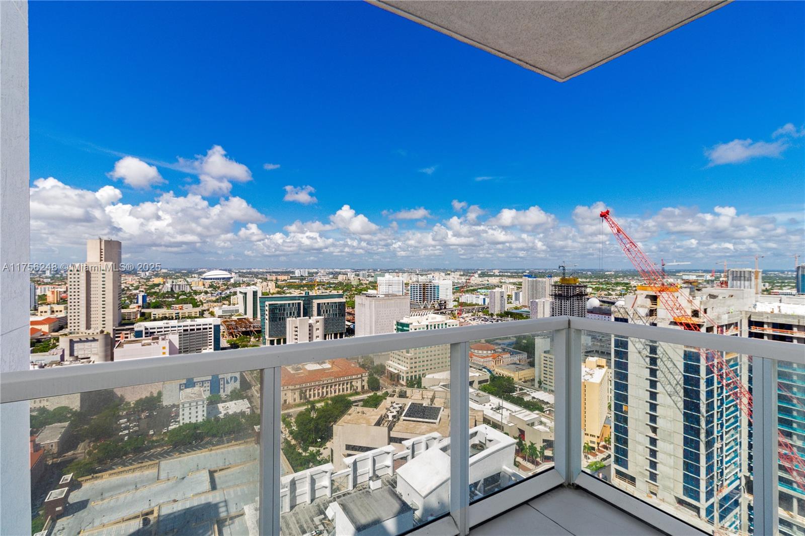 A high-rise balcony overlooks a dense urban cityscape with a large construction crane — 253 NE 2nd St # 3702, Miami FL 33132, MIAMI, FL