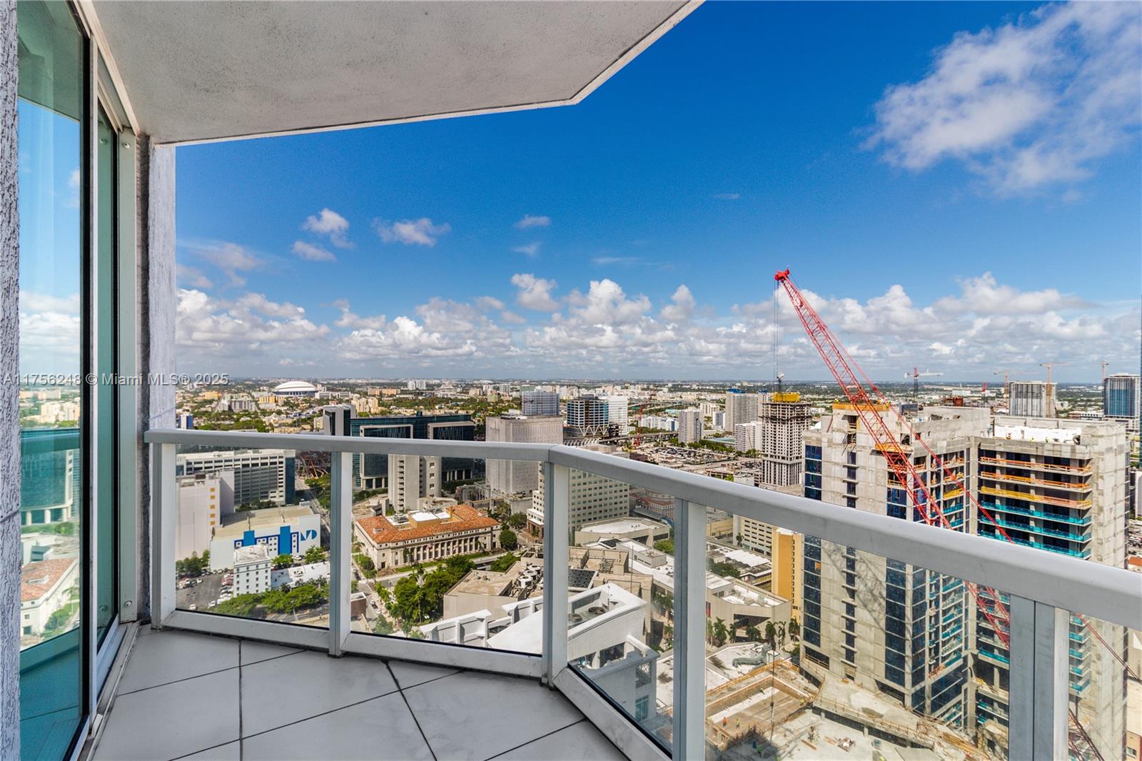 A high-rise balcony with a glass railing overlooks a city skyline and a construction site — 253 NE 2nd St # 3702, Miami FL 33132, MIAMI, FL