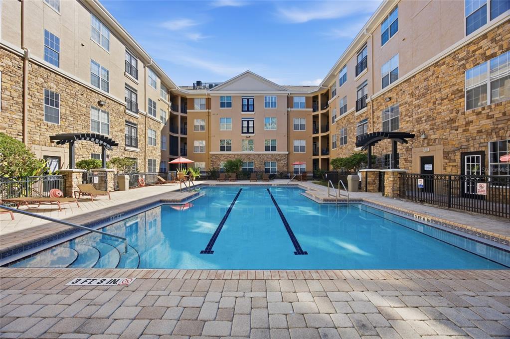 A multi-story apartment building exterior features tan stucco walls, balconies, and a central palm tree — 4221 W SPRUCE STREET UNIT 2328, TAMPA, FL