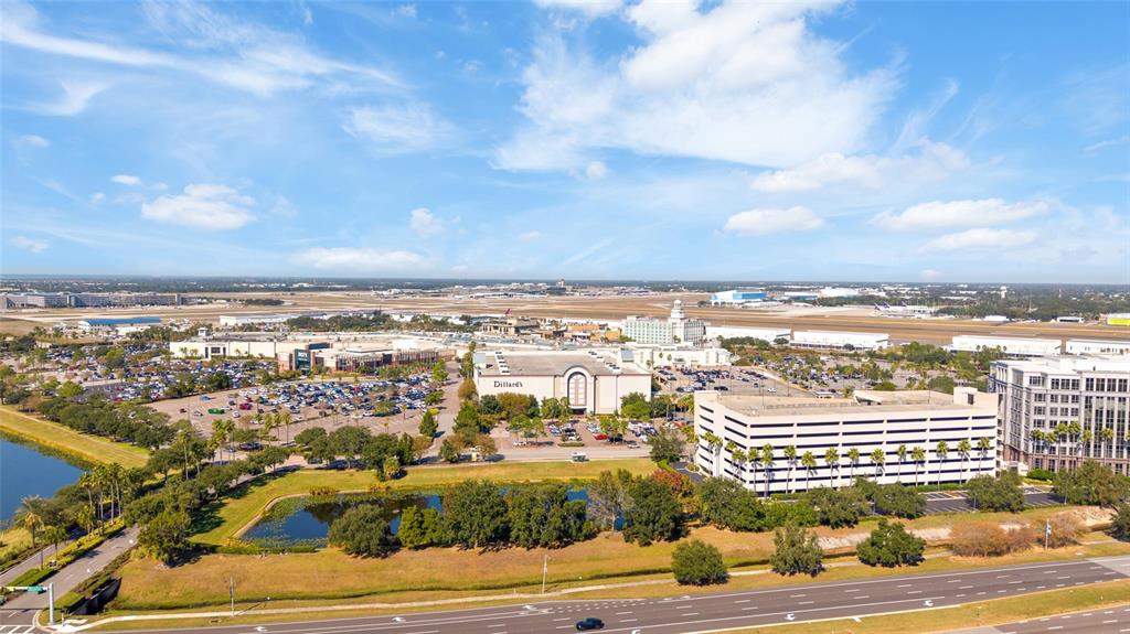 An aerial view shows a shopping mall, parking garage, and pond near an airport runway — 4221 W SPRUCE STREET UNIT 2328, TAMPA, FL