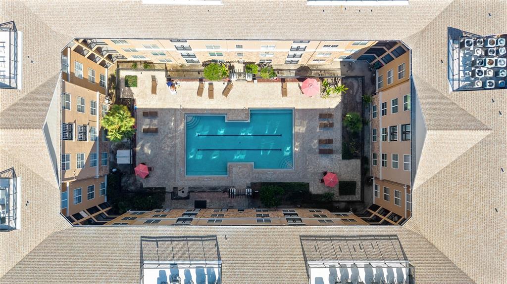 An aerial view of an apartment complex courtyard featuring a swimming pool and lounge chairs — 4221 W SPRUCE STREET UNIT 2328, TAMPA, FL