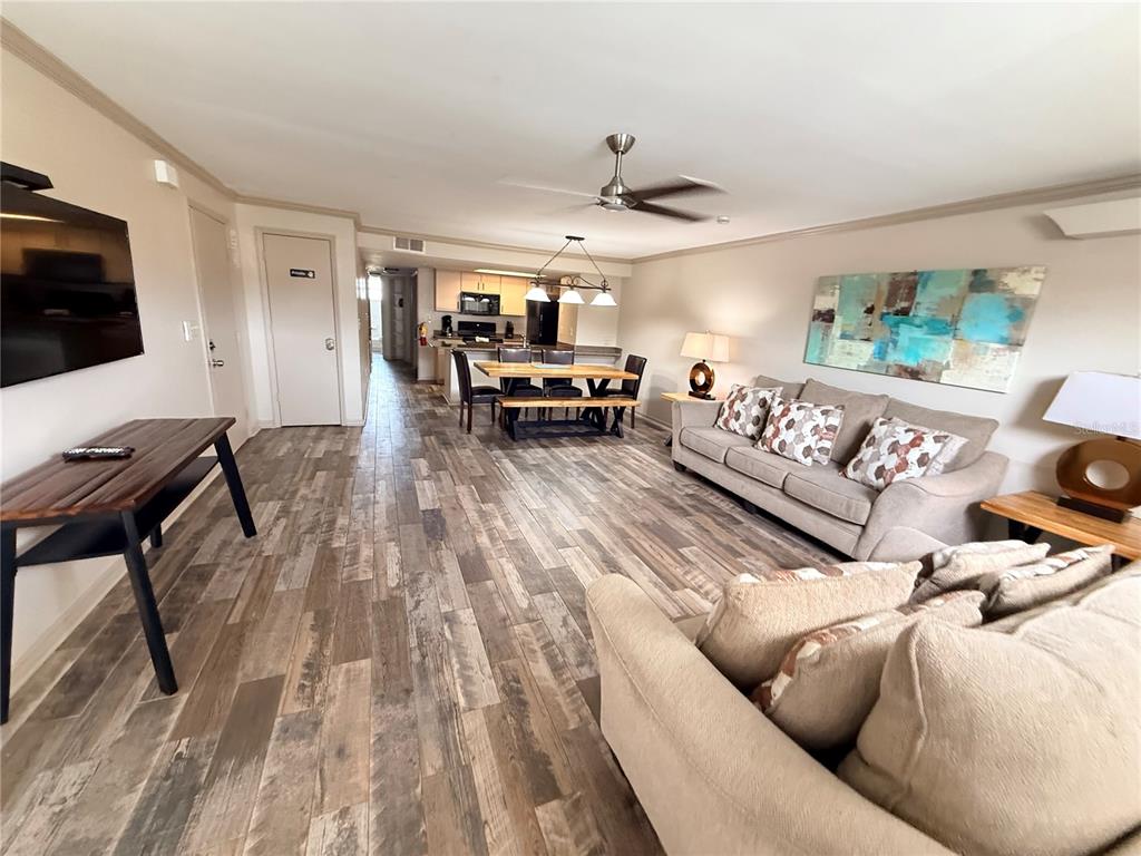 An open-concept living and dining area features wood-look flooring, a ceiling fan, and neutral walls — 2490 SWEETWATER CLUB CIRCLE UNIT 67, KISSIMMEE, FL