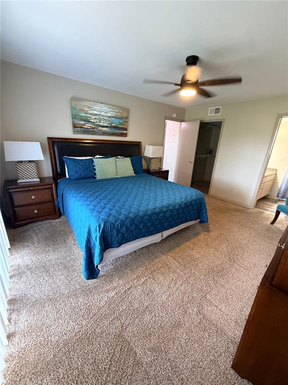 A bedroom features a king-sized bed with a blue quilt, carpeted floors, and a ceiling fan — 2490 SWEETWATER CLUB CIRCLE UNIT 67, KISSIMMEE, FL
