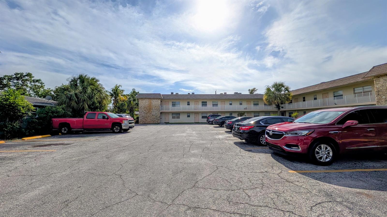 A parking lot sits in front of a two-story apartment building under a sunny sky — 2301 SE 4th Street # 12, Boynton Beach FL 33435, BOYNTON BEACH, FL