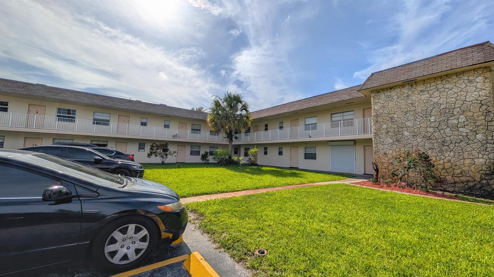 A two-story apartment building with a central lawn, palm tree, and parking area — 2301 SE 4th Street # 12, Boynton Beach FL 33435, BOYNTON BEACH, FL