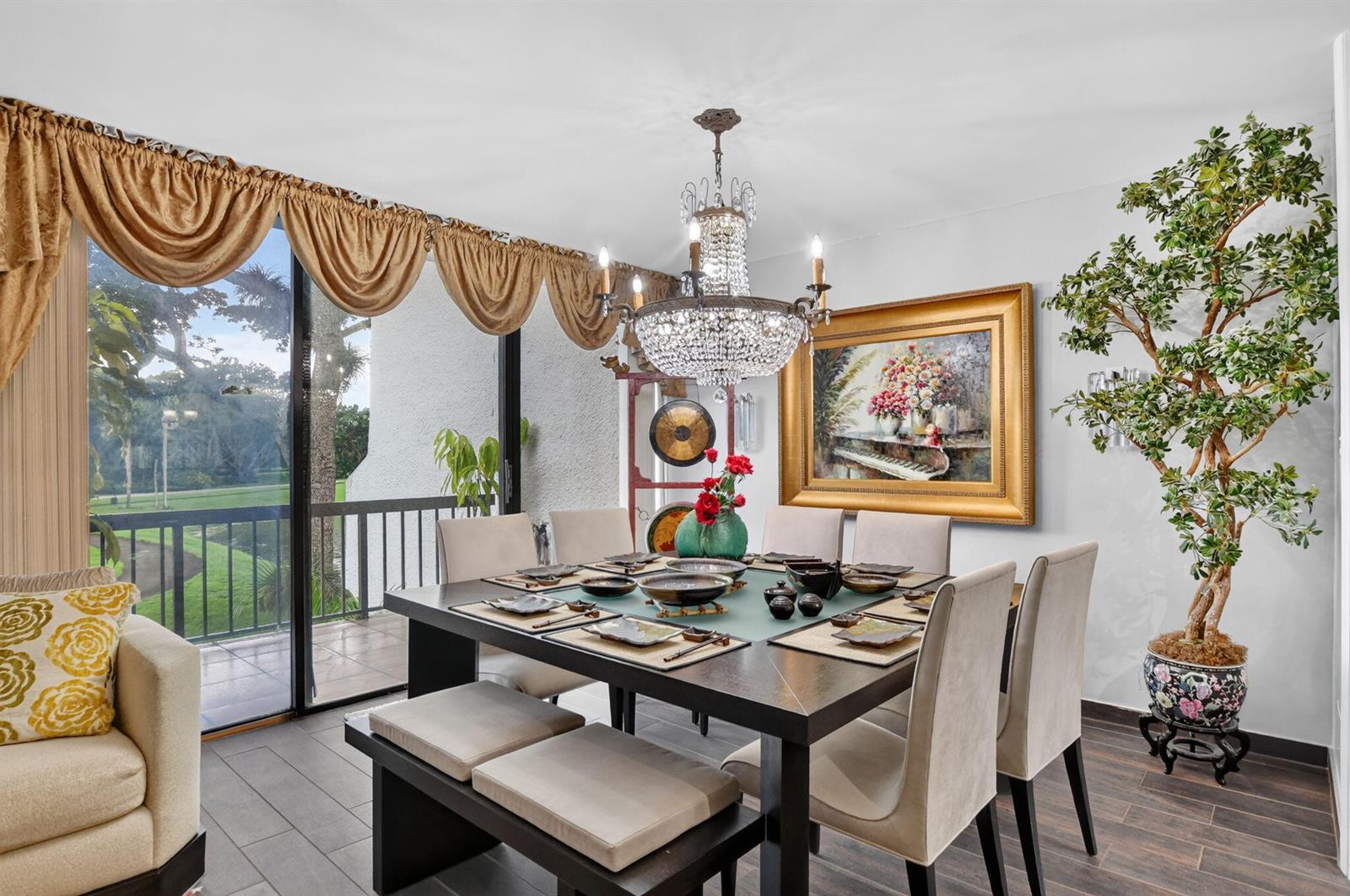 A dining room features a dark wood table, crystal chandelier, and a sliding glass door — 2805 Bridgewood Drive, Boca Raton FL 33434, BOCA RATON, FL