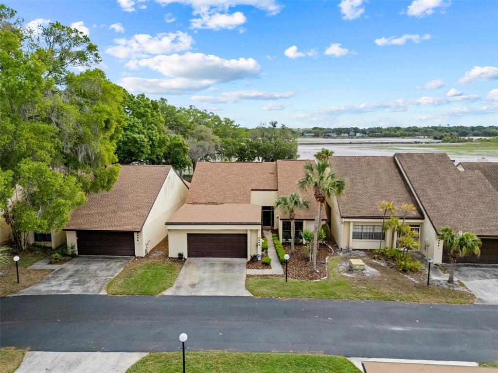 An aerial view shows three attached houses with brown roofs and driveways facing a road — 4365 CREEKWOOD LANE UNIT 4365, MULBERRY, FL