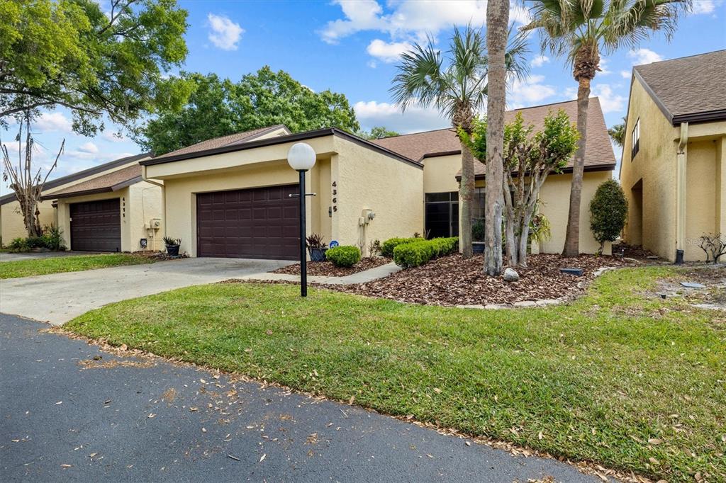 A single-story tan stucco townhouse with a brown garage door and a palm tree — 4365 CREEKWOOD LANE UNIT 4365, MULBERRY, FL