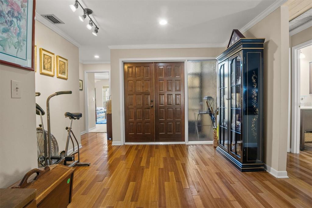 An entryway features hardwood floors, a double wooden door, and a tall black display cabinet — 4365 CREEKWOOD LANE UNIT 4365, MULBERRY, FL