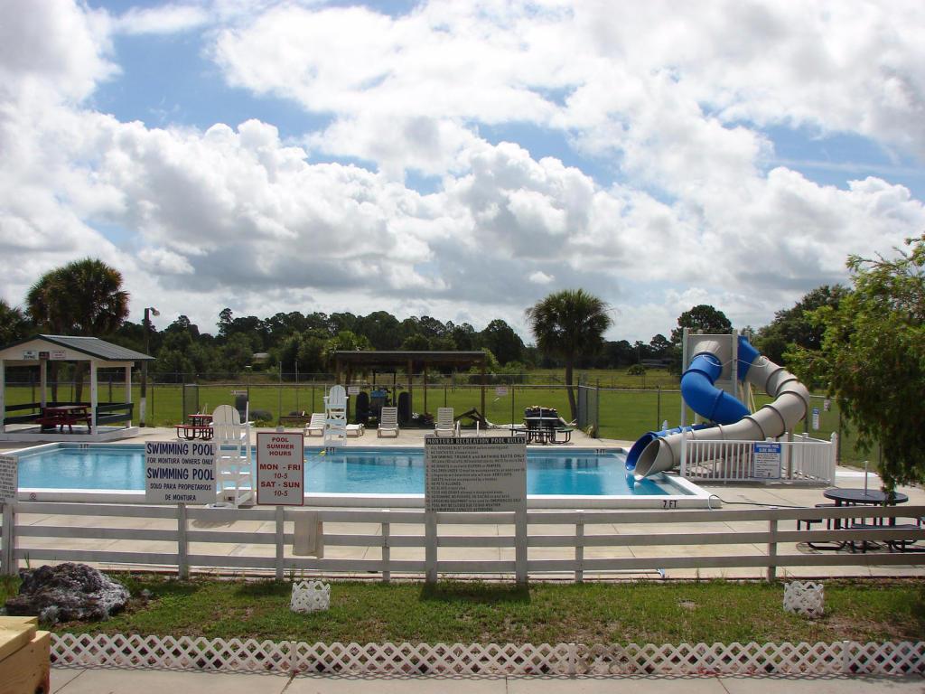A fenced outdoor swimming pool features a blue water slide and a covered seating area — 730 S Willow, Clewiston FL 33440, CLEWISTON, FL
