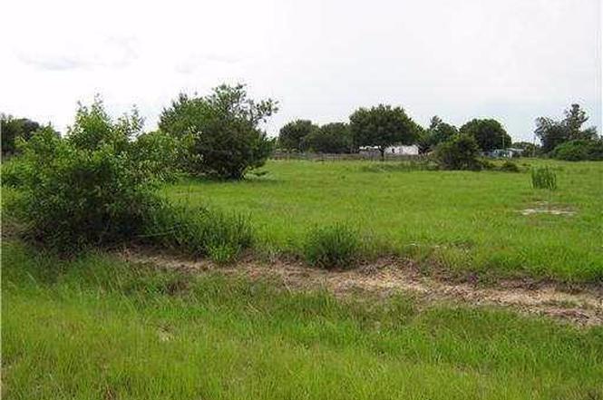 A grassy, undeveloped lot features scattered trees and a dirt path under a cloudy sky — 730 S Willow, Clewiston FL 33440, CLEWISTON, FL