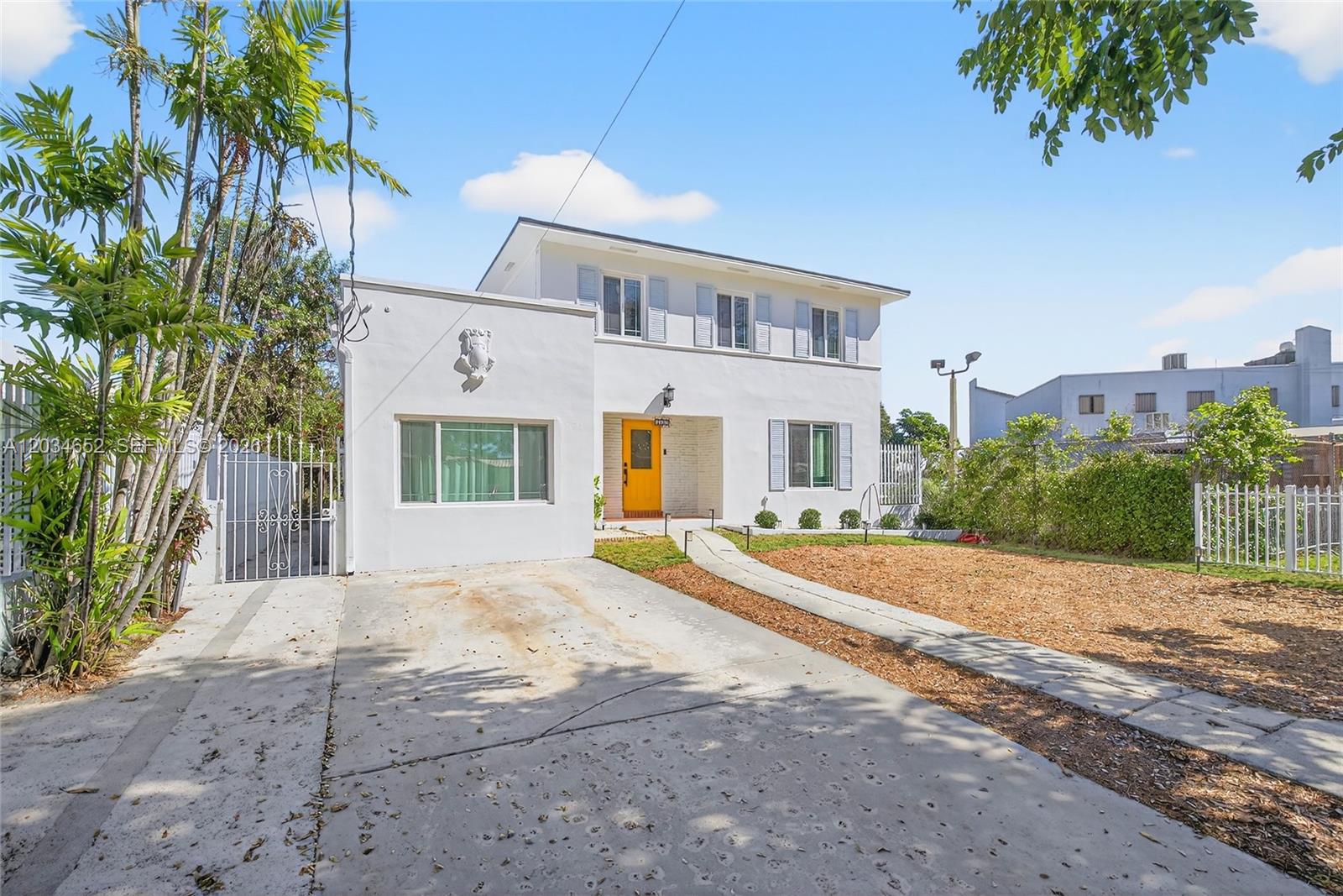 A two-story white house features a bright yellow front door and a concrete driveway — 2431 SW 4th St, Miami FL 33135, MIAMI, FL