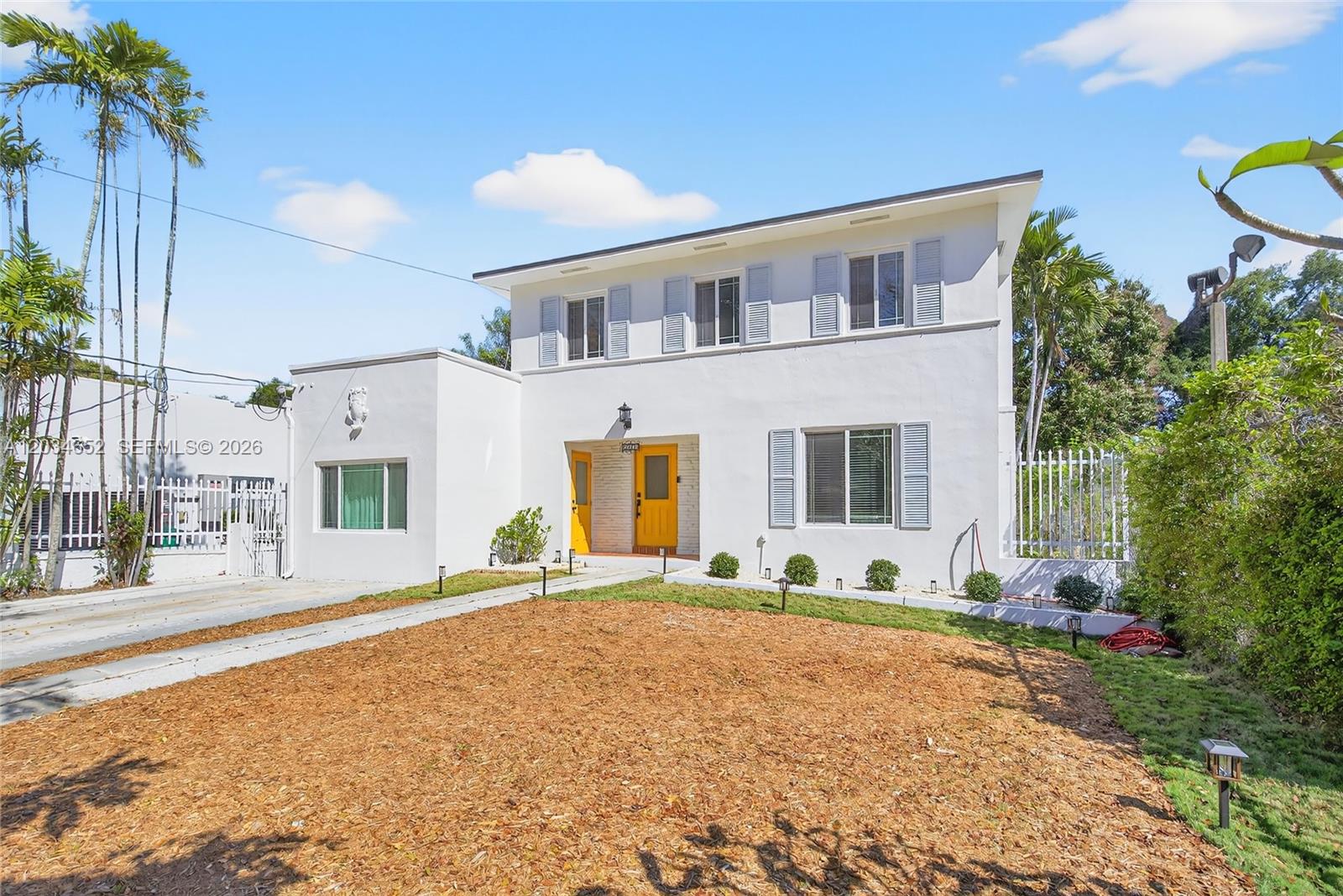 A two-story white house features a flat roof, yellow doors, and a wood-mulched front yard — 2431 SW 4th St, Miami FL 33135, MIAMI, FL