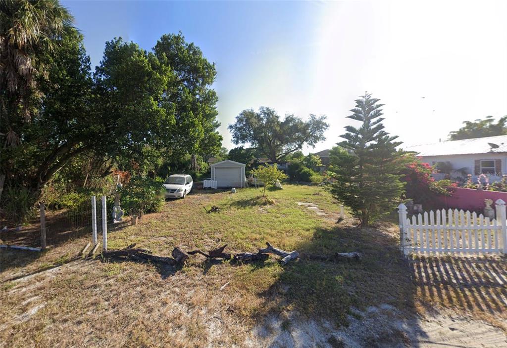 A grassy lot features a detached garage, a parked car, and a white picket fence — 3817 N 58TH STREET, TAMPA, FL