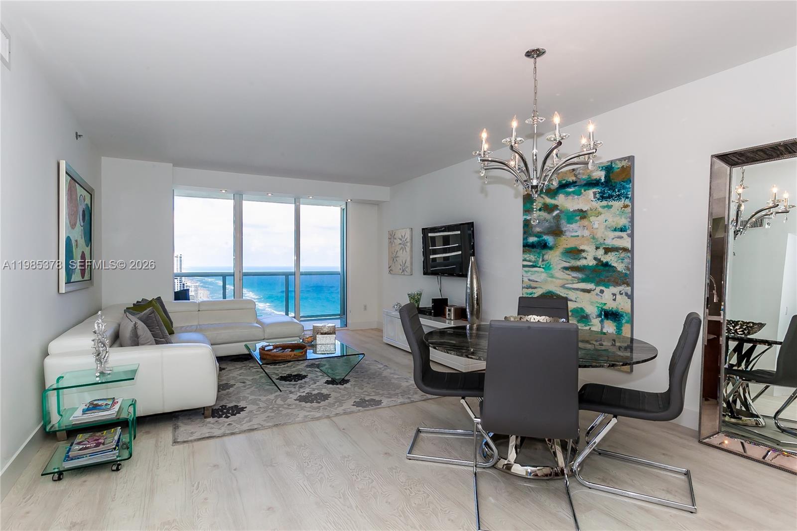 A living and dining room features a white sectional, glass table, and ocean view — 1830 S OCEAN DR. # 3711, Hallandale Beach FL 33009, HALLANDALE BEACH, FL