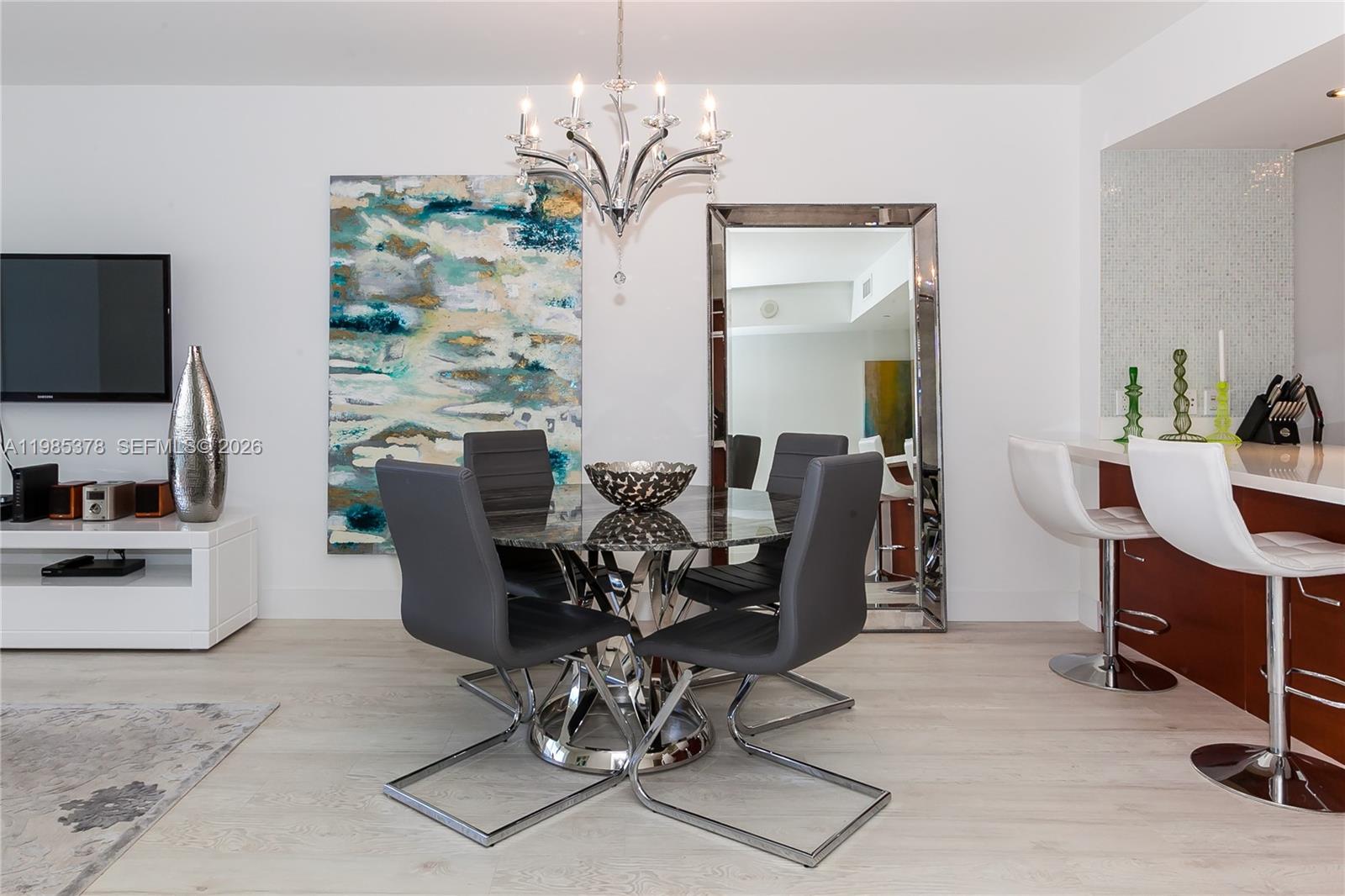 A dining area features a glass-topped table, four gray chairs, a chandelier, and a mirror — 1830 S OCEAN DR. # 3711, Hallandale Beach FL 33009, HALLANDALE BEACH, FL