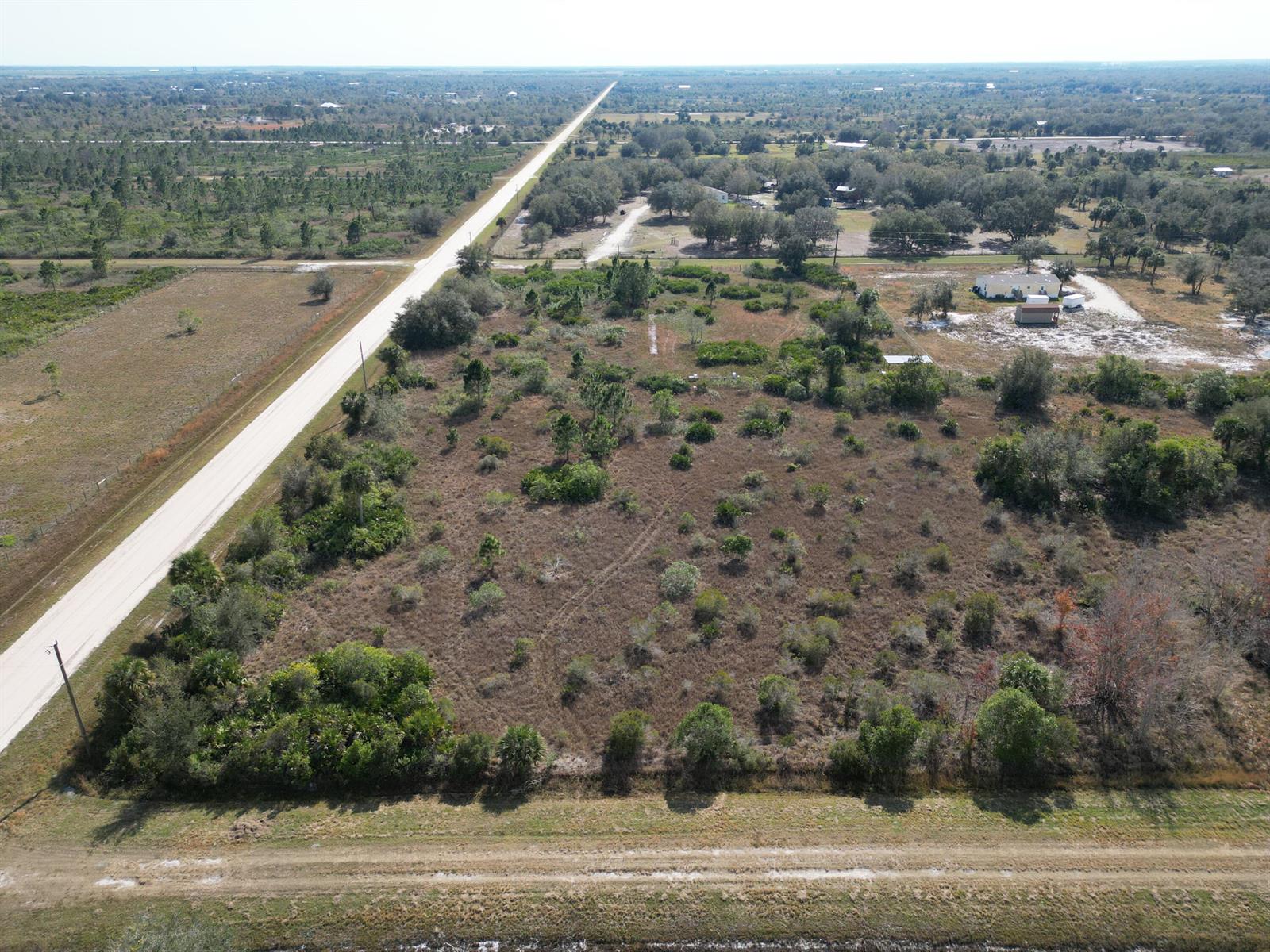 An aerial view shows a vacant, brush-covered lot adjacent to a paved road — 16010 NW 278th Street, Okeechobee FL 34972, OKEECHOBEE, FL