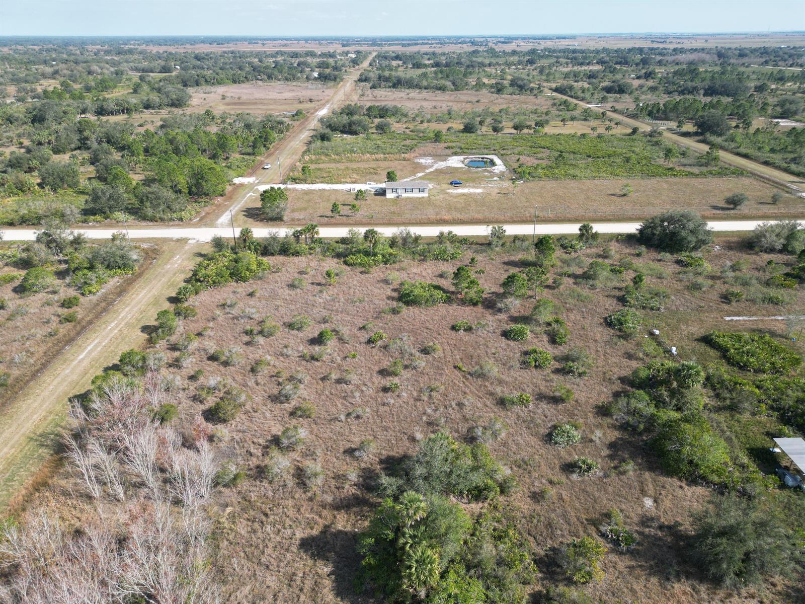 An aerial view shows a rural property with a small house, pond, and dirt roads — 16010 NW 278th Street, Okeechobee FL 34972, OKEECHOBEE, FL
