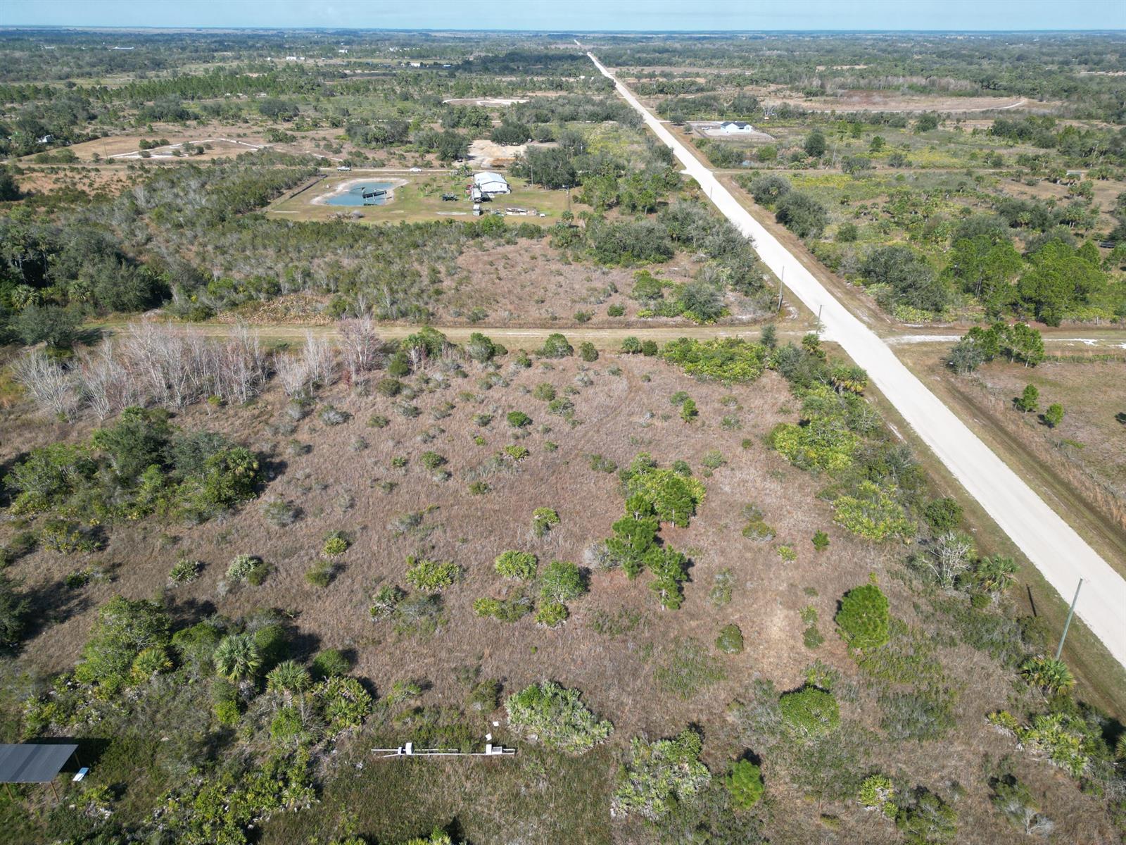 An aerial view shows a large, undeveloped grassy lot next to a paved road — 16010 NW 278th Street, Okeechobee FL 34972, OKEECHOBEE, FL