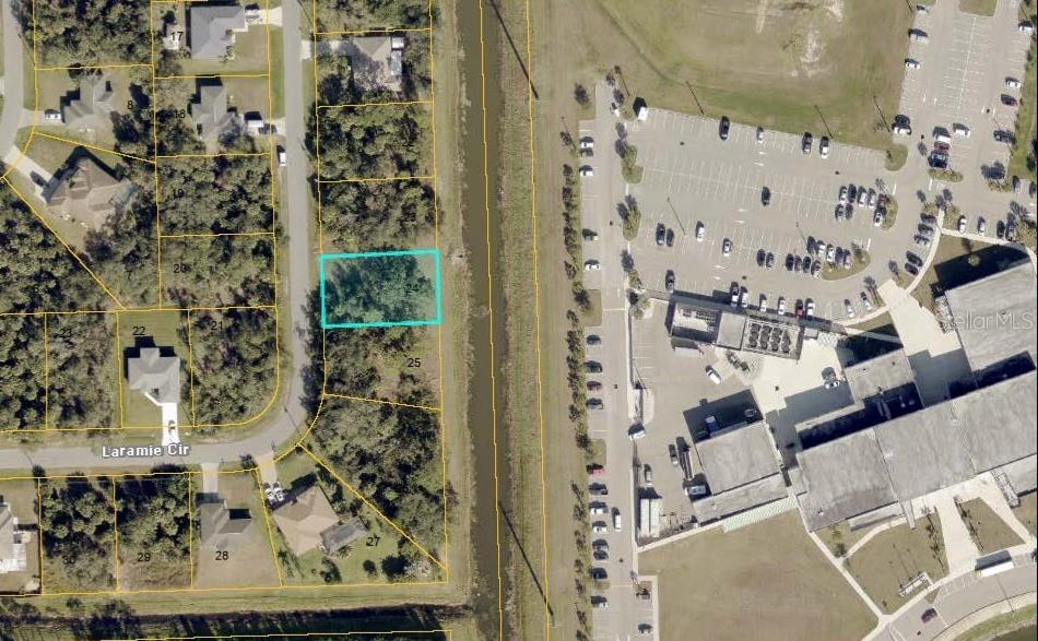 This aerial map shows a highlighted vacant residential lot adjacent to a commercial parking area — Lot 24 LARAMIE CIRCLE, NORTH PORT, FL