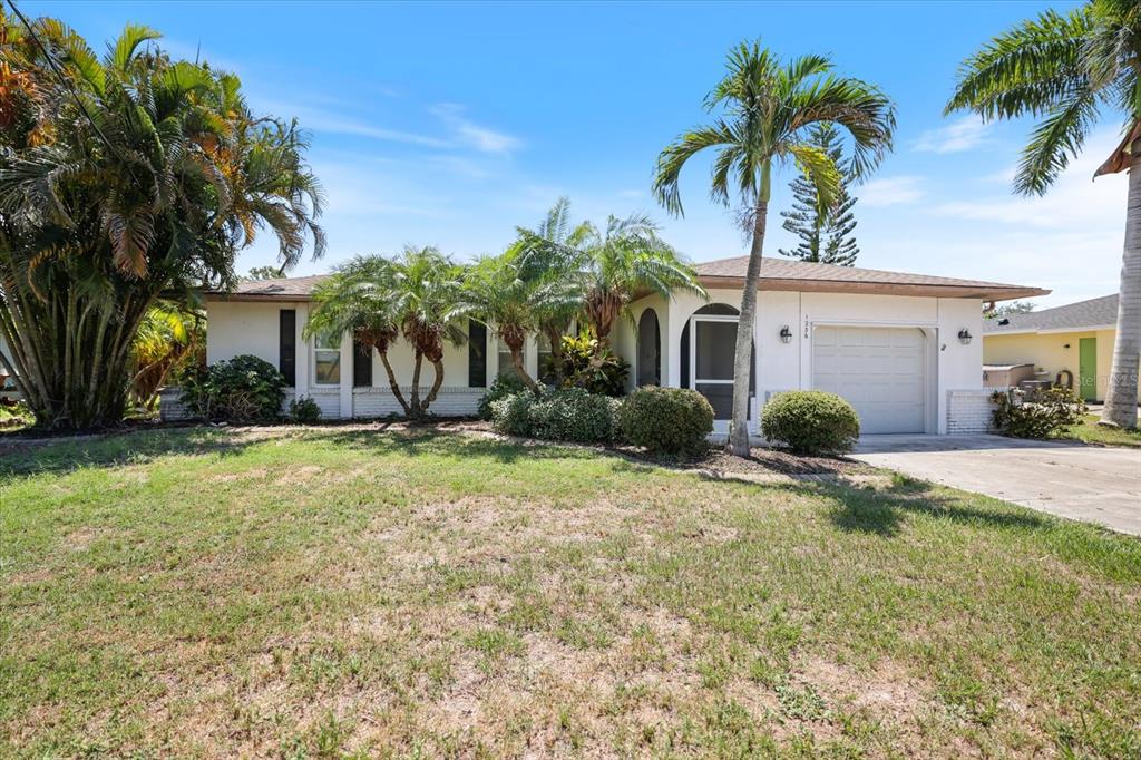 A single-story house with a white exterior, a one-car garage, and several palm trees — 1236 GAYLE AVE, NOKOMIS, FL