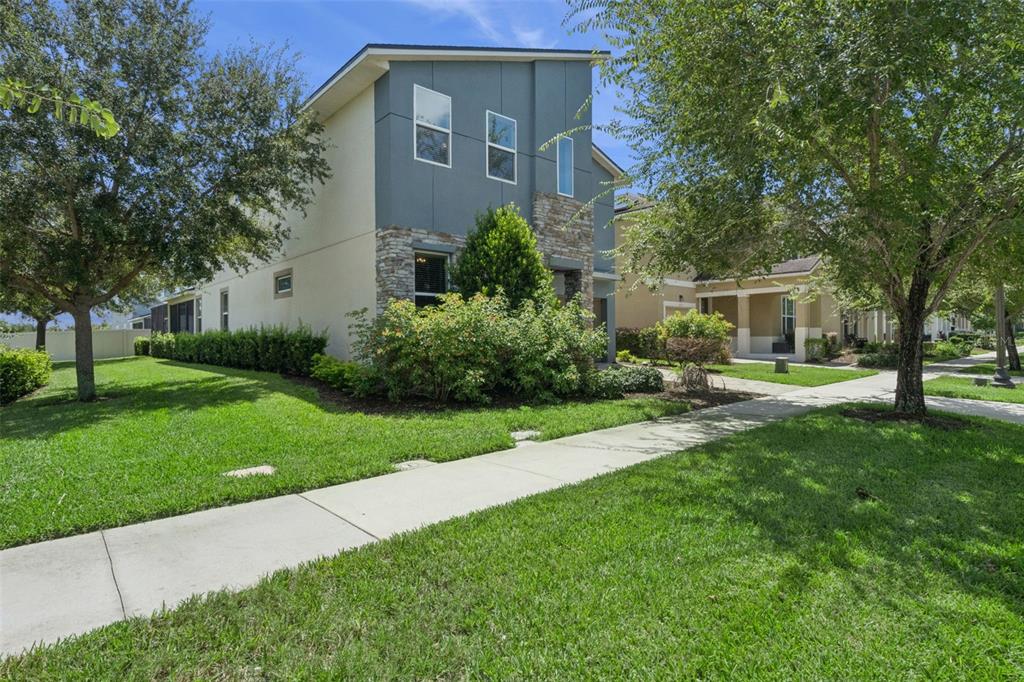 A two-story house with a stone facade and gray siding stands beside a sidewalk — 1633 NASSAU POINT TRAIL, KISSIMMEE, FL