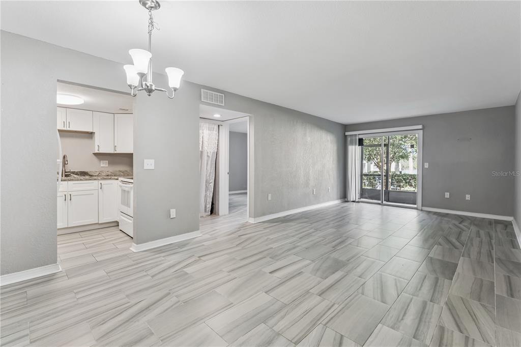 An open-concept living area with gray walls, light tile flooring, and an adjacent white kitchen — 950 LAKE DESTINY ROAD UNIT B, ALTAMONTE SPRINGS, FL