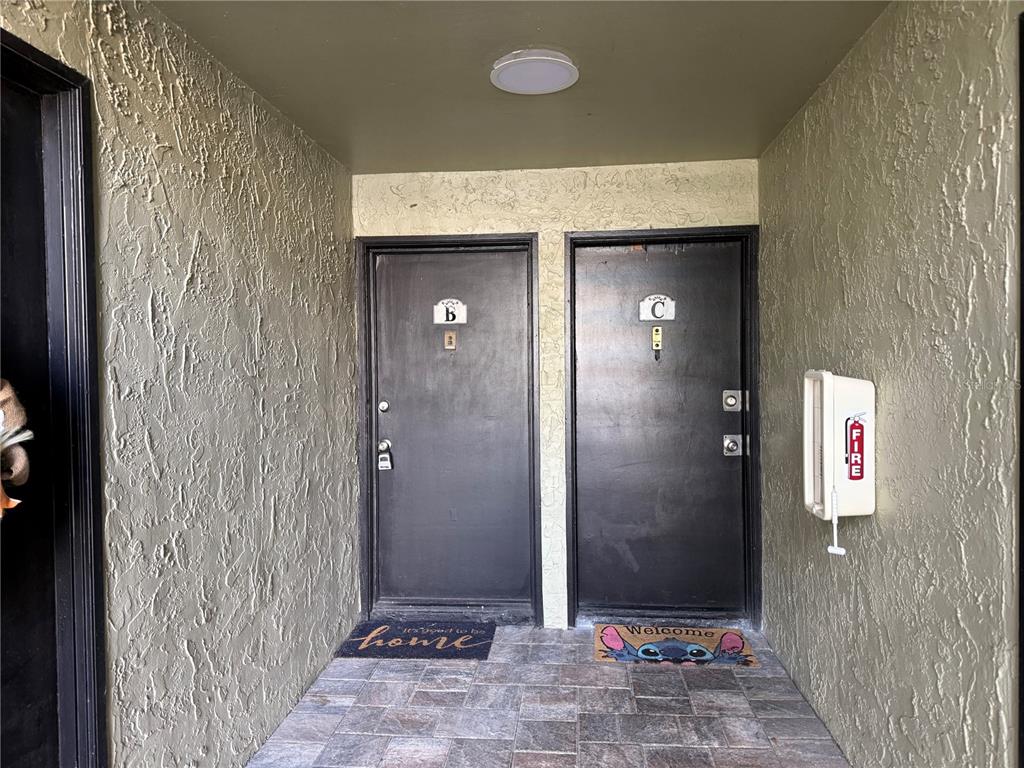 Two dark brown apartment doors labeled B and C sit side-by-side in a stucco entryway — 950 LAKE DESTINY ROAD UNIT B, ALTAMONTE SPRINGS, FL
