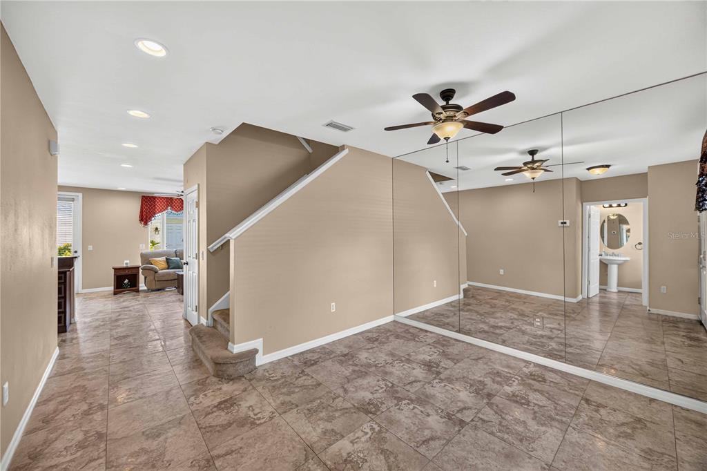 A room with tile flooring, a staircase, and a large mirrored wall reflecting a bathroom — 5653 WHITEHEAD STREET, BRADENTON, FL