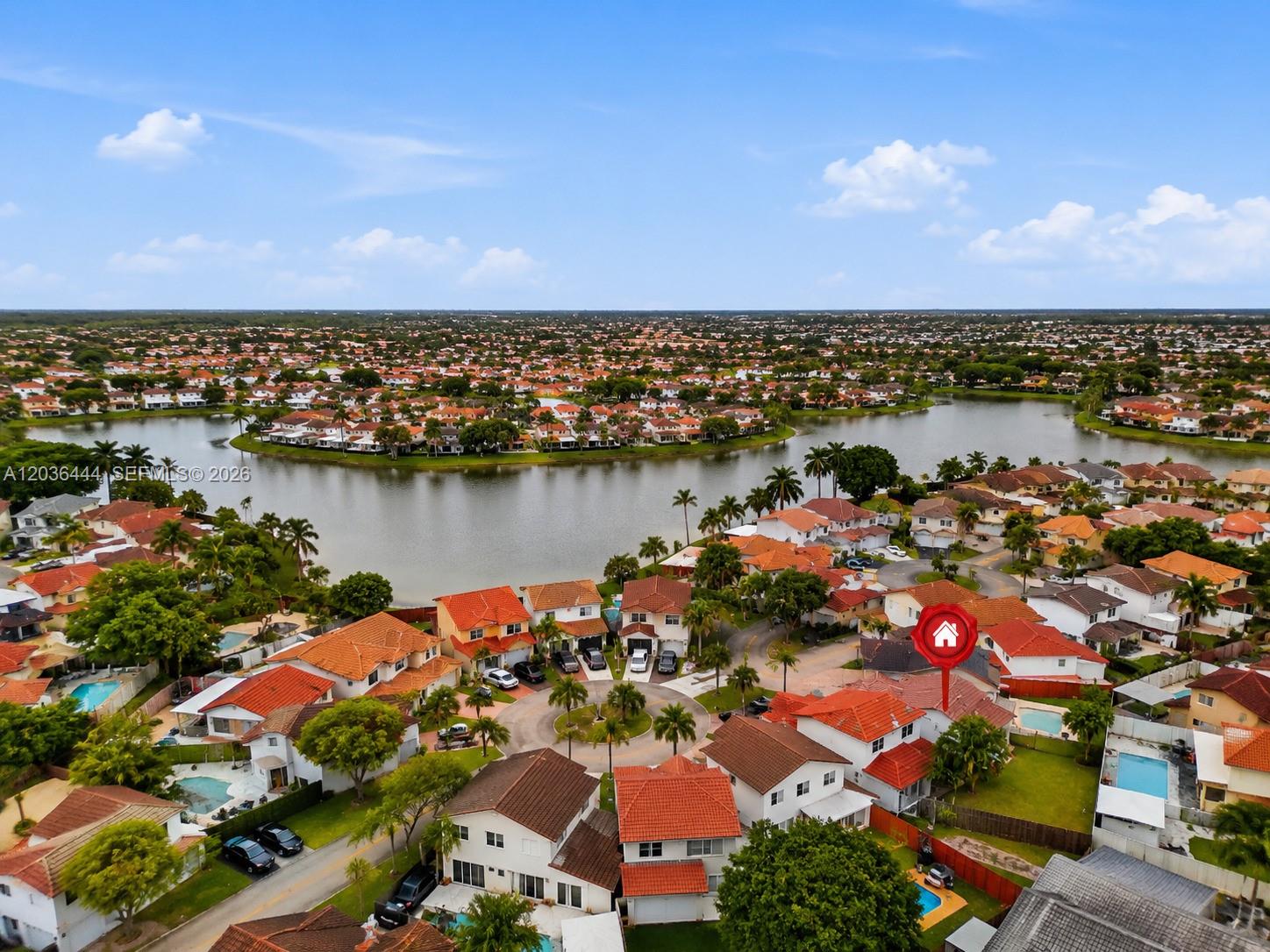 An aerial view shows a suburban neighborhood with houses surrounding a large lake — 13263 SW 9th Ter, Miami FL 33184, MIAMI, FL
