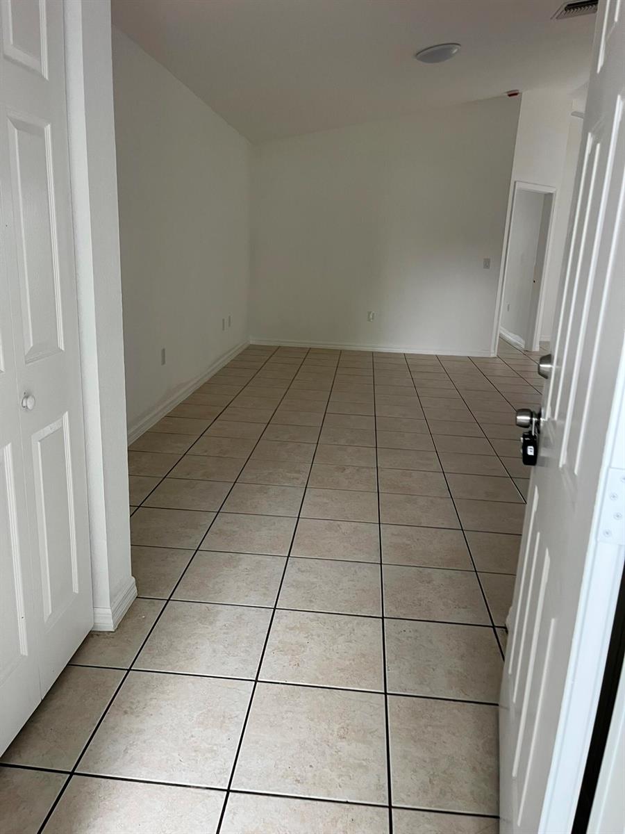 An empty room with beige tile flooring, white walls, and a white door — 3049 SE 38th Avenue, Okeechobee FL 34974, OKEECHOBEE, FL