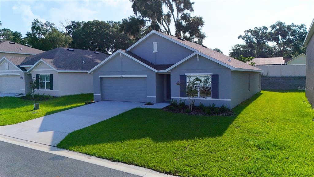 A single-story suburban house with a gray exterior, a two-car garage, and a front lawn — 11331 SE 72ND COURT, BELLEVIEW, FL