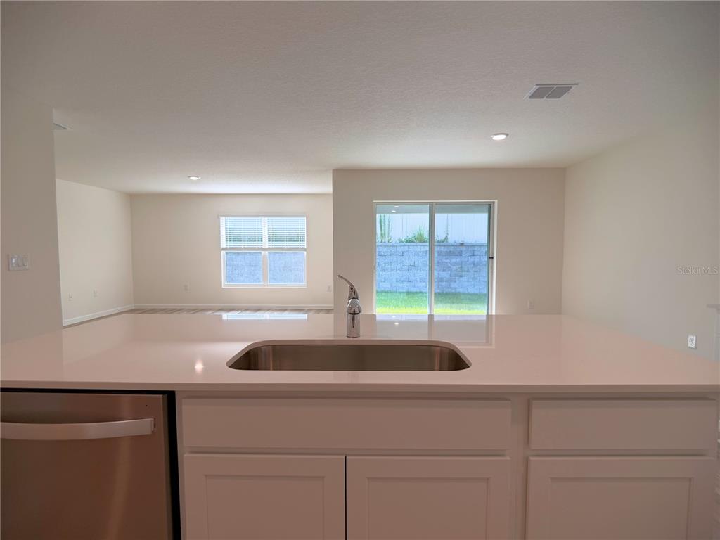 A kitchen island with a stainless steel sink faces a living area with sliding doors — 11331 SE 72ND COURT, BELLEVIEW, FL